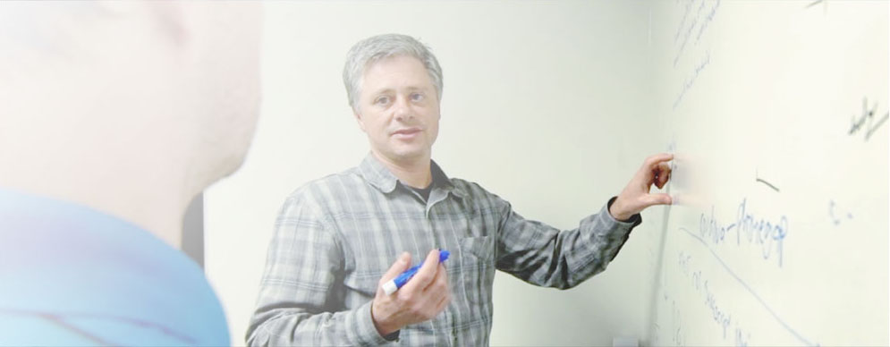 two men talking at a whiteboard