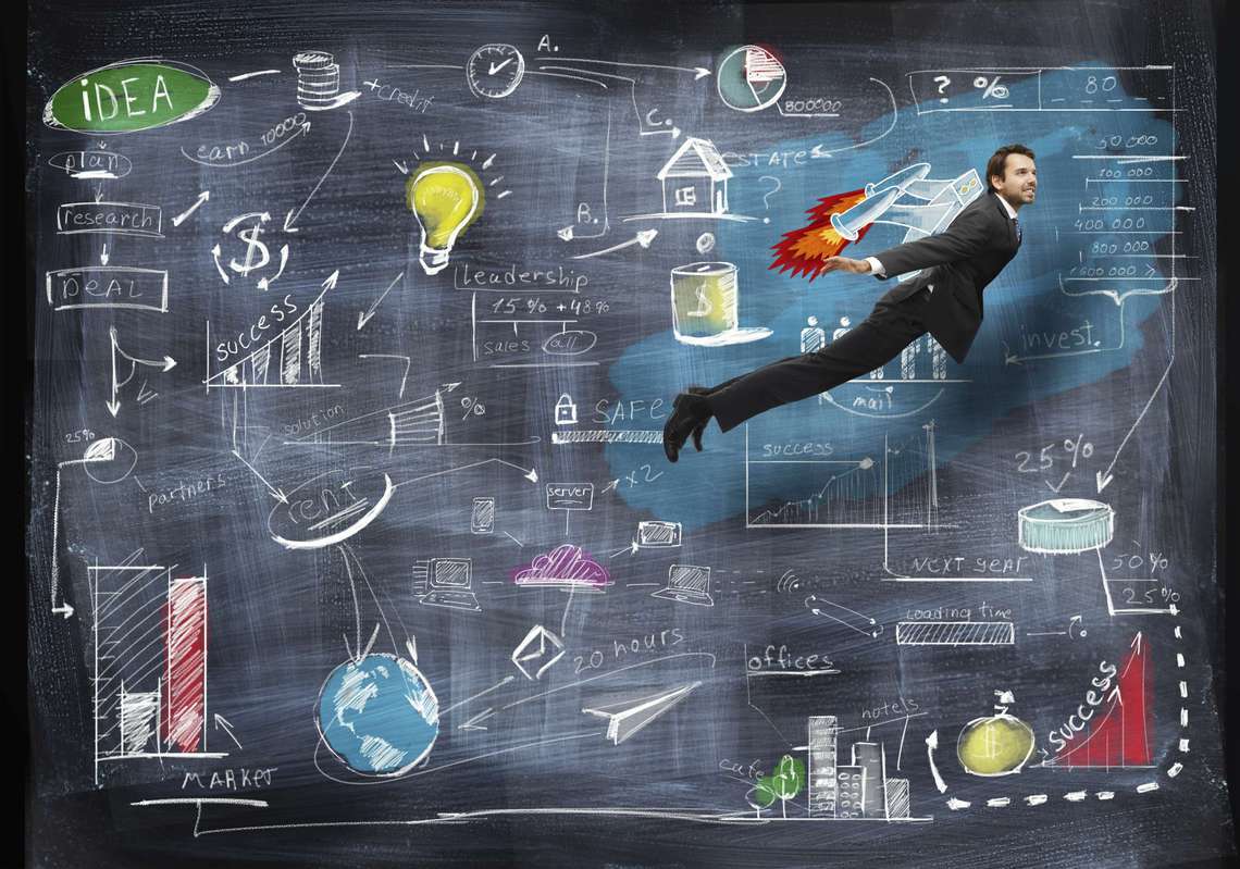 Man flying in a business suit against chalkboard.